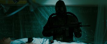 Movie still from “The Crazies” (2010), directed by Breck Eisner – A man in a gas mask is standing in a room; Medium shot, Over the shoulder angle