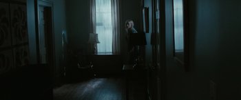 Movie still from “The Crazies” (2010), directed by Breck Eisner – A woman standing in front of a window in a dark room; Wide shot, Over the shoulder angle