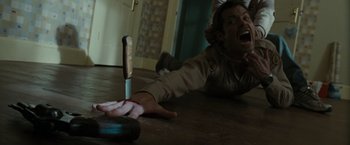 Movie still from “The Crazies” (2010), directed by Breck Eisner – A man laying on the ground with a knife in his hand; Medium shot, Overhead angle
