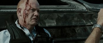 Movie still from “The Crazies” (2010), directed by Breck Eisner – A man with a bandage on his face and a bullet hole in the side of a car; Close Up shot, Over the shoulder angle