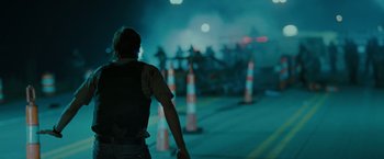 Movie still from “The Crazies” (2010), directed by Breck Eisner – A man standing in front of orange cones on a street; Medium shot, Over the shoulder angle