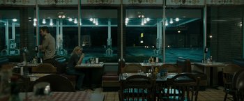 Movie still from “The Crazies” (2010), directed by Breck Eisner – A woman sitting at a table in front of a large window; Wide shot, High angle