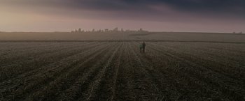 Movie still from “The Crazies” (2010), directed by Breck Eisner – Two people walking in a field with a city in the background; Extreme Wide shot, High angle