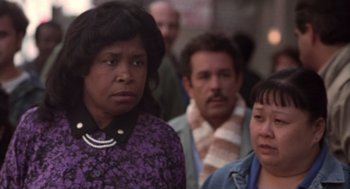 Movie still from “The Crossing Guard” (1995), directed by Sean Penn – A group of people standing next to each other on the street; Close Up shot, Over the shoulder angle