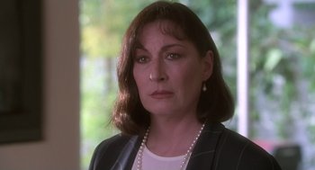 Movie still from “The Crossing Guard” (1995), directed by Sean Penn – A person wearing a suit and pearl necklace; Close Up shot, Over the shoulder angle