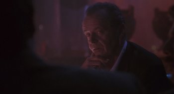 Movie still from “The Crossing Guard” (1995), directed by Sean Penn – An older man sitting at a table in a dark room; Close Up shot, Over the shoulder angle