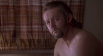 Movie still from “The Crossing Guard” (1995), directed by Sean Penn – A man with long hair and a beard is posing for the camera; Close Up shot, Over the shoulder angle