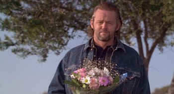 Movie still from “The Crossing Guard” (1995), directed by Sean Penn – A man holding a bouquet of flowers in his hands; Close Up shot, Over the shoulder angle