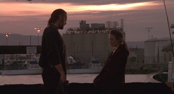 Movie still from “The Crossing Guard” (1995), directed by Sean Penn – A man and a woman standing next to each other near a body of water; Medium shot, Low angle