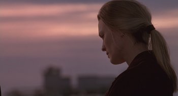 Movie still from “The Crossing Guard” (1995), directed by Sean Penn – A young woman is standing in front of a sunset; Close Up shot, Over the shoulder angle