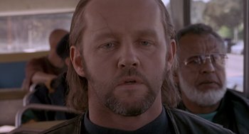 Movie still from “The Crossing Guard” (1995), directed by Sean Penn – A person with long hair and a beard; Close Up shot, Over the shoulder angle