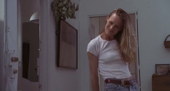 Movie still from “The Crossing Guard” (1995), directed by Sean Penn – A woman in white shirt and jeans standing next to a door; Medium shot, Low angle