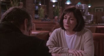 Movie still from “The Crossing Guard” (1995), directed by Sean Penn – An older woman sitting at a table in front of an older man; Close Up shot, Over the shoulder angle