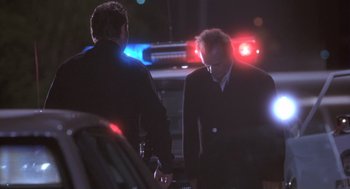 Movie still from “The Crossing Guard” (1995), directed by Sean Penn – Two men in suits are talking to a police car; Medium shot, Low angle