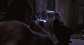 Movie still from “The Crossing Guard” (1995), directed by Sean Penn – A man in a black suit is smoking a cigarette; Medium shot, Over the shoulder angle