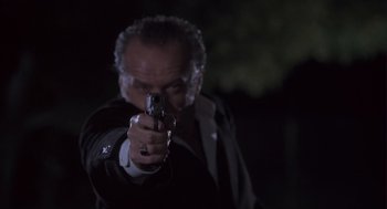 Movie still from “The Crossing Guard” (1995), directed by Sean Penn – A man with a gun pointing at the camera; Close Up shot, Low angle