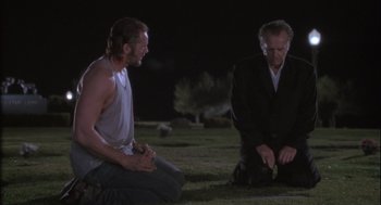 Movie still from “The Crossing Guard” (1995), directed by Sean Penn – Two men kneeling in the grass at night; Medium shot, Low angle