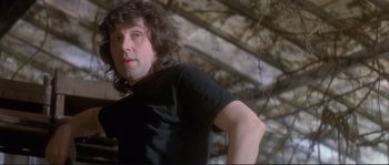 Movie still from “The Crying Game” (1992), directed by Neil Jordan – A man in a black t - shirt standing next to a tree; Close Up shot, Low angle