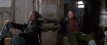 Movie still from “The Crying Game” (1992), directed by Neil Jordan – Two men sitting next to each other in a room; Medium shot, Low angle