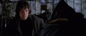 Movie still from “The Crying Game” (1992), directed by Neil Jordan – A man sitting in front of another man in a dark room; Close Up shot, Over the shoulder angle