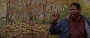 Movie still from “The Crying Game” (1992), directed by Neil Jordan – A man in a denim jacket pointing to the sky in the woods; Close Up shot, Over the shoulder angle