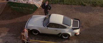 Movie still from “The Crying Game” (1992), directed by Neil Jordan – A man standing next to a white car on a dirt road; Wide shot, High angle