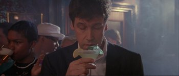 Movie still from “The Crying Game” (1992), directed by Neil Jordan – A man in a black jacket is drinking a drink; Close Up shot, Low angle