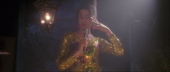 Movie still from “The Crying Game” (1992), directed by Neil Jordan – A woman in a gold sequined dress holding a microphone; Medium shot, Low angle