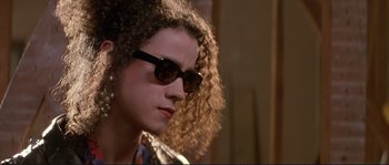 Movie still from “The Crying Game” (1992), directed by Neil Jordan – A young woman with curly hair wearing sunglasses; Close Up shot, Low angle