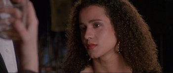 Movie still from “The Crying Game” (1992), directed by Neil Jordan – A young woman with long curly black hair wearing red lipstick; Close Up shot, Low angle