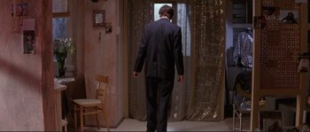 Movie still from “The Crying Game” (1992), directed by Neil Jordan – A man in a suit walking in front of a window; Wide shot, Low angle