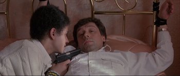 Movie still from “The Crying Game” (1992), directed by Neil Jordan – A young boy holding a gun next to a man in a bed; Close Up shot, Low angle
