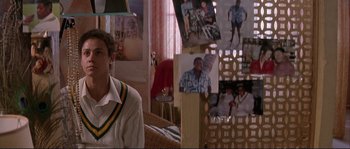 Movie still from “The Crying Game” (1992), directed by Neil Jordan – A man sitting in front of a wall of pictures; Medium shot, High angle