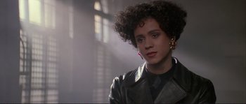 Movie still from “The Crying Game” (1992), directed by Neil Jordan – A woman in a black leather jacket and earrings; Close Up shot, Over the shoulder angle