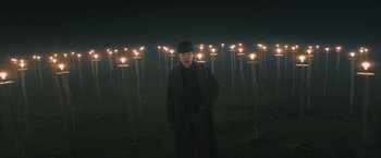 Movie still from “The Current War: Director's Cut” (2017), directed by Alfonso Gomez-Rejon – A man standing in front of a bunch of lit candles; Wide shot, High angle