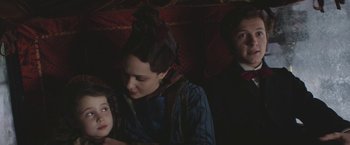 Movie still from “The Current War: Director's Cut” (2017), directed by Alfonso Gomez-Rejon – A woman and two men sitting on a couch; Medium shot, Over the shoulder angle