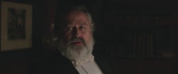Movie still from “The Current War: Director's Cut” (2017), directed by Alfonso Gomez-Rejon – An old man with a beard wearing a suit and bow tie; Close Up shot, Low angle