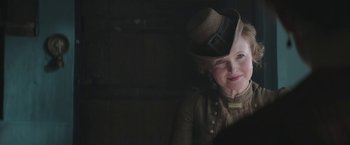 Movie still from “The Current War: Director's Cut” (2017), directed by Alfonso Gomez-Rejon – A woman wearing a hat in a dark room; Close Up shot, Over the shoulder angle