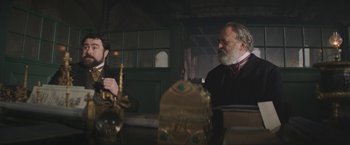 Movie still from “The Current War: Director's Cut” (2017), directed by Alfonso Gomez-Rejon – Two men standing next to each other in front of a building; Medium shot, Low angle