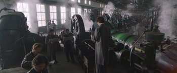 Movie still from “The Current War: Director's Cut” (2017), directed by Alfonso Gomez-Rejon – A group of people standing around a machine; Wide shot, Low angle