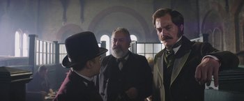 Movie still from “The Current War: Director's Cut” (2017), directed by Alfonso Gomez-Rejon – A group of men standing next to each other in a room; Medium shot, Over the shoulder angle