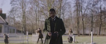 Movie still from “The Current War: Director's Cut” (2017), directed by Alfonso Gomez-Rejon – A man in a green coat is standing in a park; Medium shot, Over the shoulder angle