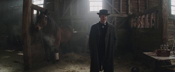 Movie still from “The Current War: Director's Cut” (2017), directed by Alfonso Gomez-Rejon – A man standing in a barn next to a horse; Medium shot, Low angle