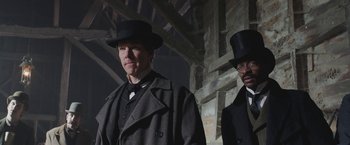 Movie still from “The Current War: Director's Cut” (2017), directed by Alfonso Gomez-Rejon – A man in a top hat standing next to another man in a suit; Medium shot, Over the shoulder angle
