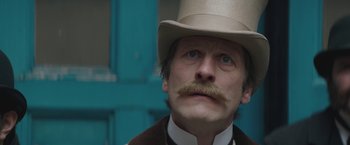 Movie still from “The Current War: Director's Cut” (2017), directed by Alfonso Gomez-Rejon – A person wearing a hat with a mustache; Close Up shot, Low angle