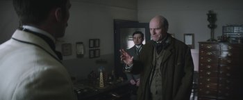 Movie still from “The Current War: Director's Cut” (2017), directed by Alfonso Gomez-Rejon – Two men standing in front of a mirror in a room; Medium shot, Over the shoulder angle