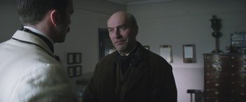 Movie still from “The Current War: Director's Cut” (2017), directed by Alfonso Gomez-Rejon – An older man wearing a suit and bow tie; Close Up shot, Over the shoulder angle