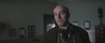 Movie still from “The Current War: Director's Cut” (2017), directed by Alfonso Gomez-Rejon – An older man wearing a suit and bow tie; Close Up shot, Low angle