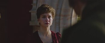 Movie still from “The Current War: Director's Cut” (2017), directed by Alfonso Gomez-Rejon – A woman in a red dress looking at the camera; Close Up shot, Over the shoulder angle