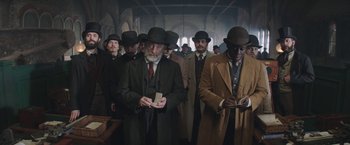 Movie still from “The Current War: Director's Cut” (2017), directed by Alfonso Gomez-Rejon – A group of men standing around each other in a room; Medium shot, Low angle